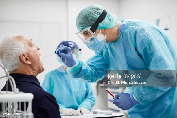 medico che prende il test del tampone alla gola da paziente maschio, pcr - abbigliamento da lavoro foto e immagini stock