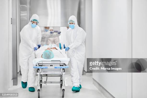 doctors pushing patient on gurney in corridor - coronavirus patient stock pictures, royalty-free photos & images