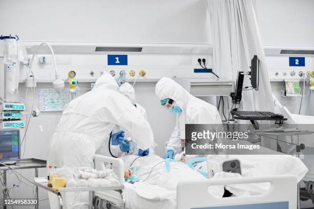 trabalhadores da linha de frente tratando paciente do sexo masculino na uti - unidade de tratamento intensivo - fotografias e filmes do acervo