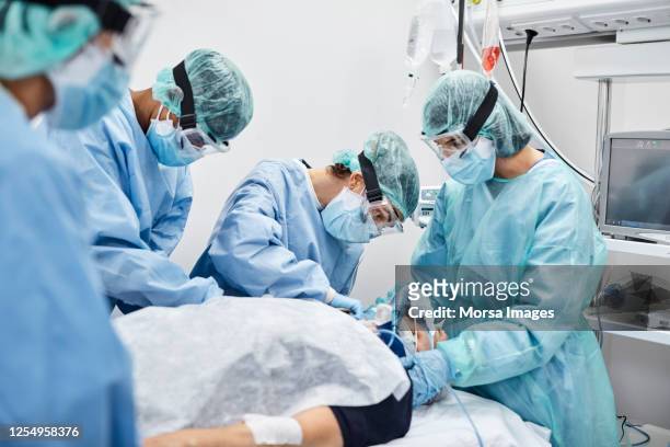 team of doctors and nurses operating male patient - protective workwear stock pictures, royalty-free photos & images