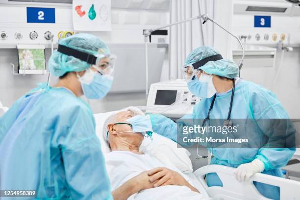 female doctor talking with patient along coworker - pandemic illness imagens e fotografias de stock