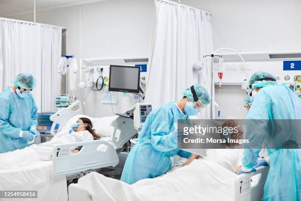 ärzte und krankenschwestern kümmern sich um patienten auf der intensivstation - pandemic illness stock-fotos und bilder