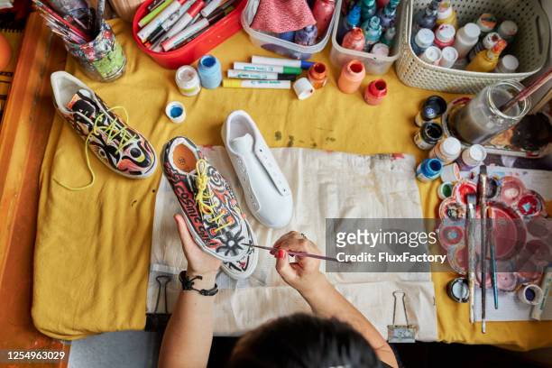 abstract female artist painitng sneakers in a colorful way - multi coloured shoe imagens e fotografias de stock