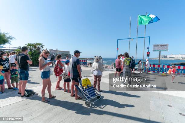 People queue up at beach capacity control measures before being allowed to enter Riazor beach on July 7, 2020 in A Coruna, Spain. Since June 22 to...