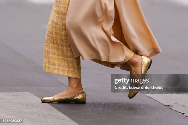 Passerby wears yellow checked wool knitter pants, golden flat ballerina shoes, on July 04, 2020 in Paris, France.