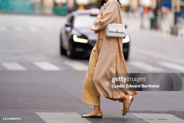 Passerby wears yellow checked wool knitted pants, golden flat ballerina shoes, a white Chanel bag, a salmon-pink flowing long coat, on July 04, 2020...