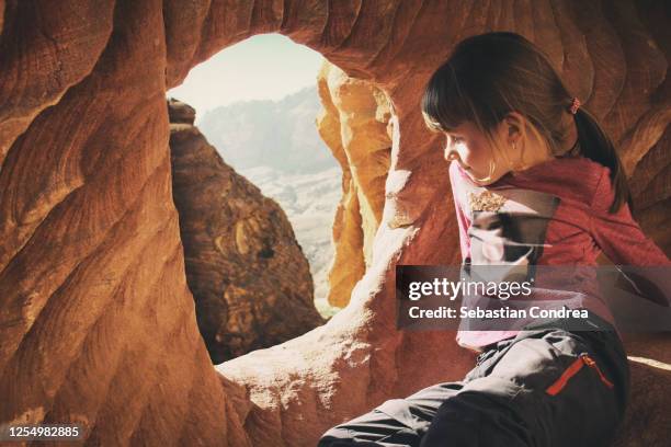 girls playing with the red stones of the canyon, look out the stone window in tomb of the soldier, petra, jordan - petra jordan stock pictures, royalty-free photos & images