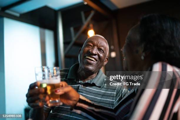 hoger paar dat bier in een staaf roostert - old couple restaurant stockfoto's en -beelden