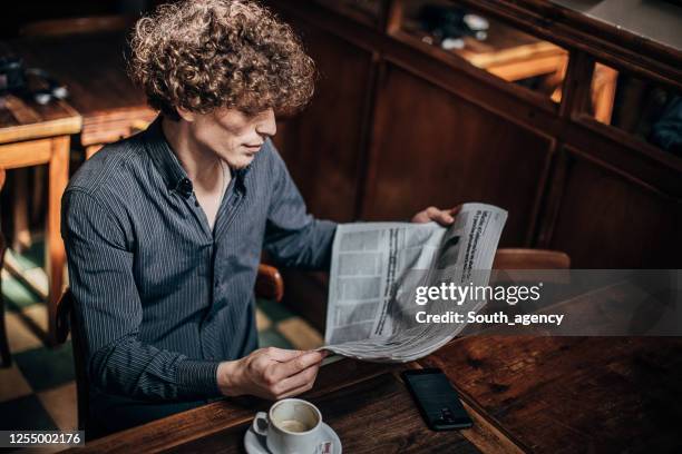 moderner herr beim zeitungslesen im café - junger mann liest zeitung stock-fotos und bilder