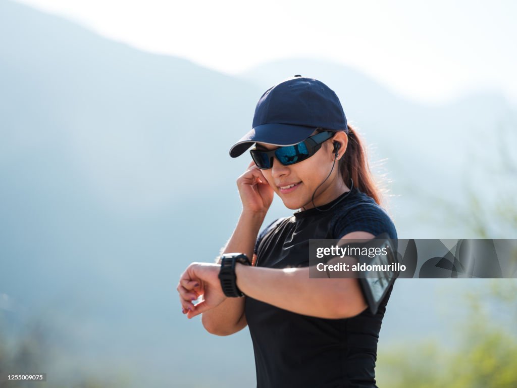 Female runner standing outside and looking at watch