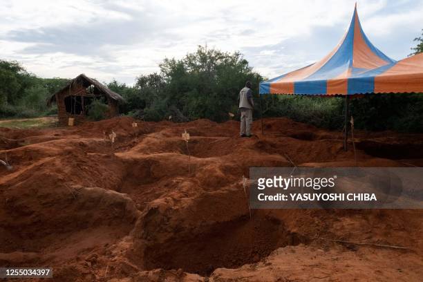 An officer of the Directorate of Criminal Investigations walks at the mass-grave site in Shakahola, outside the coastal town of Malindi, on April 25,...
