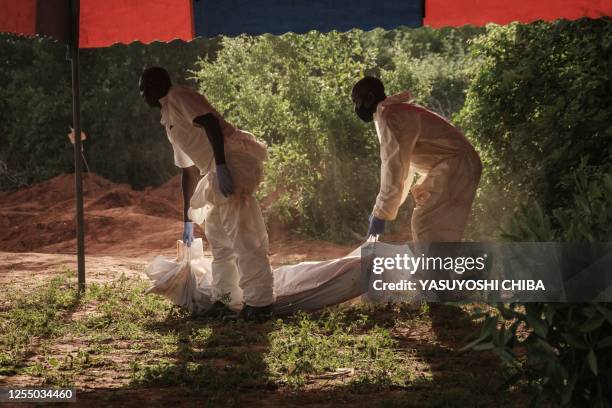 Workers carry the exhumed bodies in bodybags to the mortuary at the mass-grave site in Shakahola, outside the coastal town of Malindi, on April 25,...