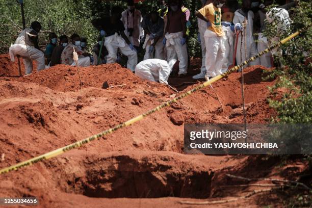 Workers dig the ground to exume bodies from the mass-grave site in Shakahola, outside the coastal town of Malindi, on April 25, 2023. The death toll...