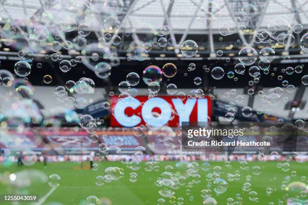 Both teams enter the pitch amongst bubbles during the Premier League match between West Ham United and Burnley FC at London Stadium on July 08, 2020...
