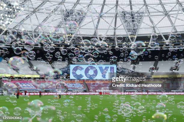 Both teams enter the pitch amongst bubbles during the Premier League match between West Ham United and Burnley FC at London Stadium on July 08, 2020...