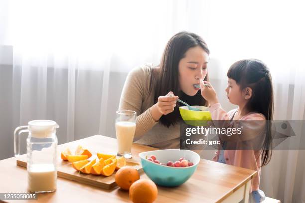 aanbiddelijk jong meisje met moeder geniet van ontbijt thuis - moeder kind zes melk stockfoto's en -beelden