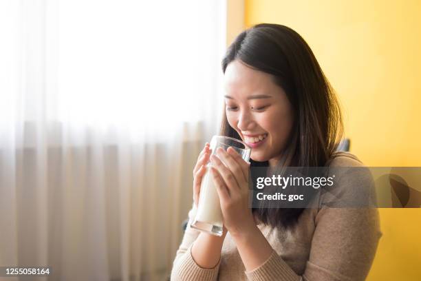 junge asiatische frau genießen milch trinken - yellow milk stock-fotos und bilder