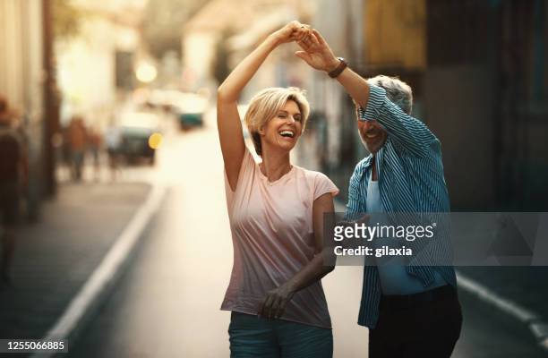 middle aged couple walking in a city street. - mid adult stock pictures, royalty-free photos & images