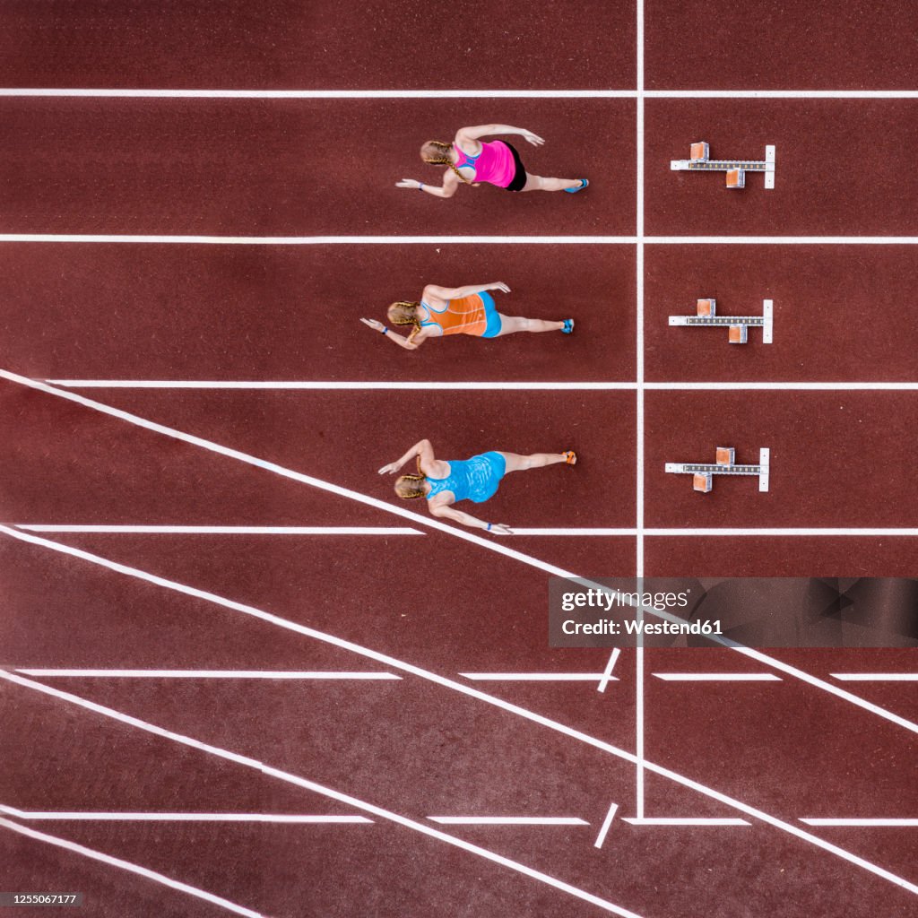 Germany, Baden Wurttemberg, Winterbach, Aerial view of three female sprinters running right after start of race