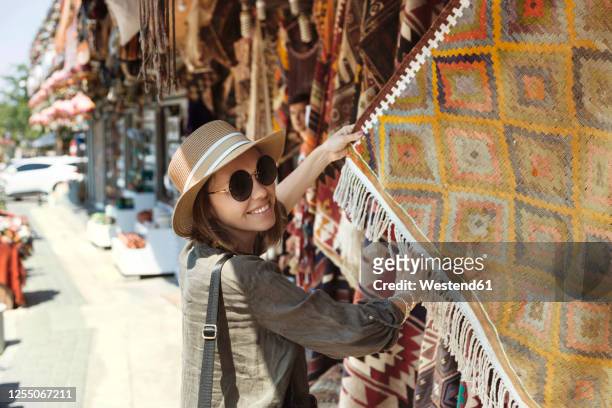 smiling young woman buying shawl at market stall in goreme, cappadocia, turkey - cappadocië stockfoto's en -beelden