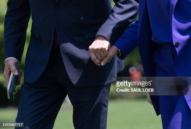 President Joe Biden and US First Lady Jill Biden hold hands after disembarking Marine One on the South Lawn of the White House in Washington, DC, on...