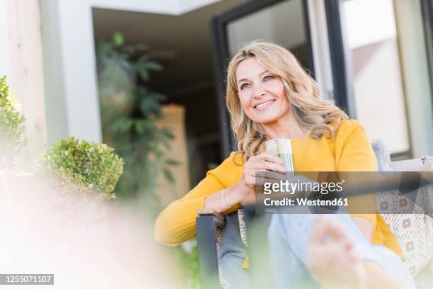 portrait of smiling mature woman sitting on terrace with green smoothie - yellow smoothie stock pictures, royalty-free photos & images