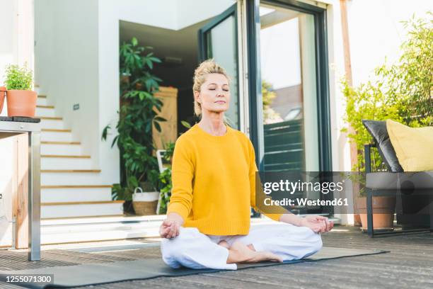 portrait of mature woman meditating on terrace - meditieren stock-fotos und bilder