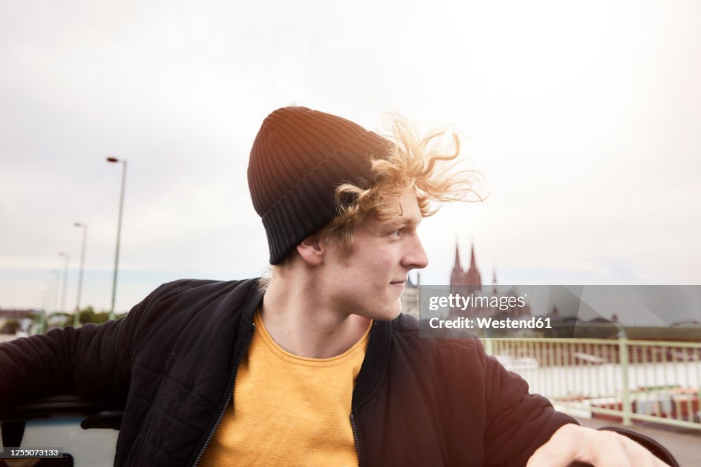 Portrait of young man with blowing hair wearing black cap, Cologne, Germany