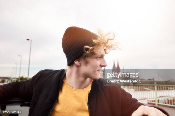 portrait of young man with blowing hair wearing black cap, cologne, germany - tousled hair man stock pictures, royalty-free photos & images