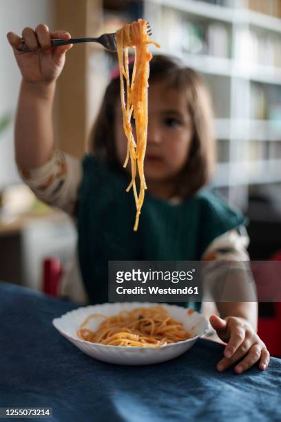 little girl's hand holding fork with spaghetti - sauce stockfoto's en -beelden