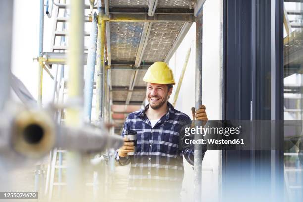 happy worker having a coffee break on a construction site - baugerüst stock-fotos und bilder