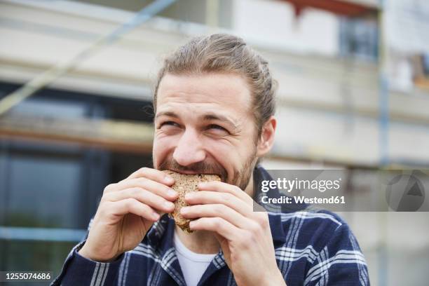 portrait of worker having lunch break on a construction site eating a bread - eating bread stockfoto's en -beelden