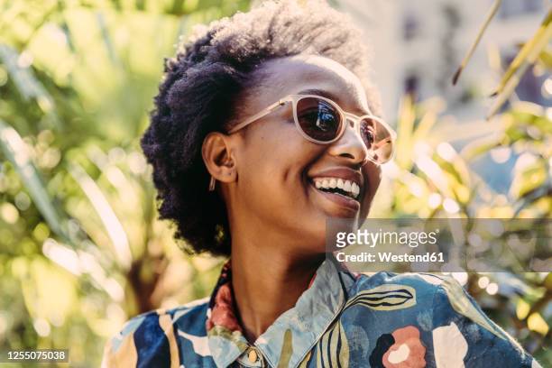 portrait of happy young woman wearing sunglasses in garden - woman sunglasses stock pictures, royalty-free photos & images