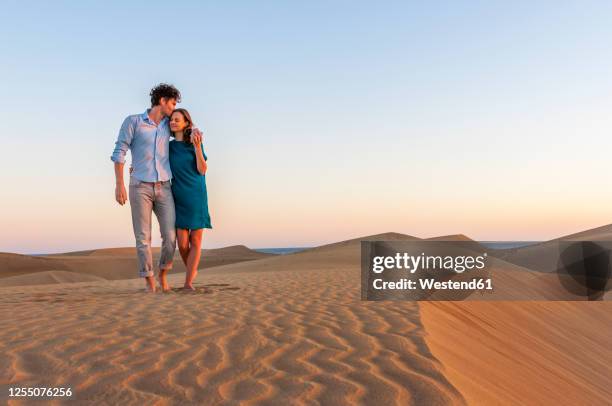 affectionate couple walking in the dunes at sunset, gran canaria, spain - couple dunes stock-fotos und bilder