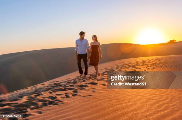 couple walking at sunset in the dunes, gran canaria, spain - couple dunes stockfoto's en -beelden