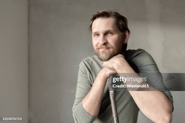 smiling man leaning on ladder during renovation - ladder leaning stock pictures, royalty-free photos & images