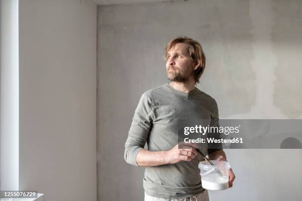 thoughtful man holding paint can at home - looking at a painting stock pictures, royalty-free photos & images