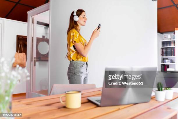 woman wearing headphones video conferencing over smart phone at home during curfew - video wall fotografías e imágenes de stock
