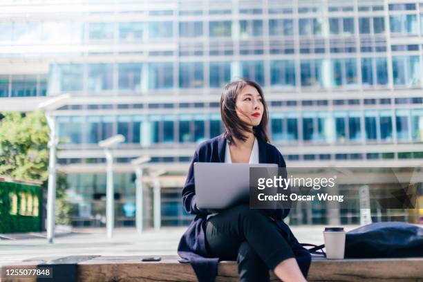 confident businesswoman working with laptop in the financial district - attesa foto e immagini stock