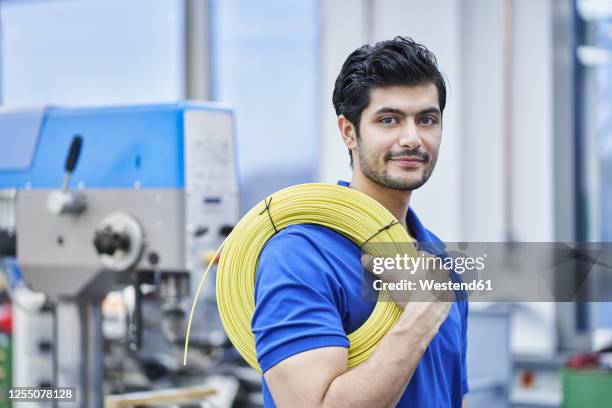 confident male worker carrying rolled up cables in factory - bundle stock pictures, royalty-free photos & images