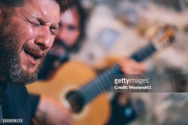 close-up of man with eyes closed singing while guitarist playing guitar in background - flamenco 個照片及圖片檔