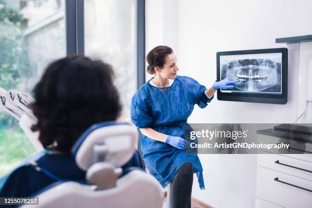 tandarts die tand röntgenfoto's verklaart aan een patiënt. - menselijk gebit stockfoto's en -beelden