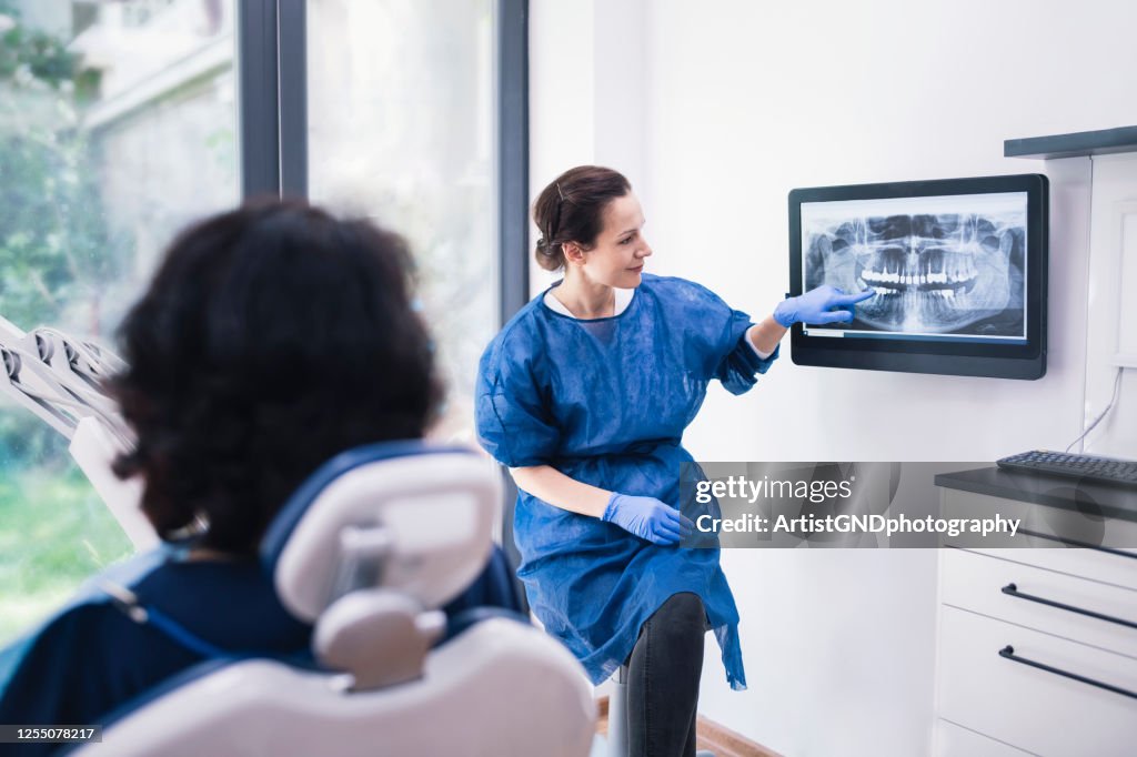 Dentist Explaining Tooth X-Rays To A Patient.