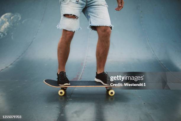 young man skateboarding on sports ramp at park - metallic shorts stock pictures, royalty-free photos & images