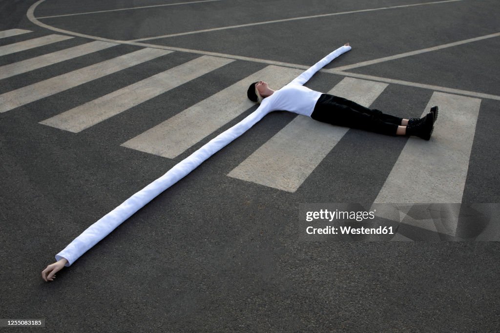Woman with long artificial hands lying on crosswalk
