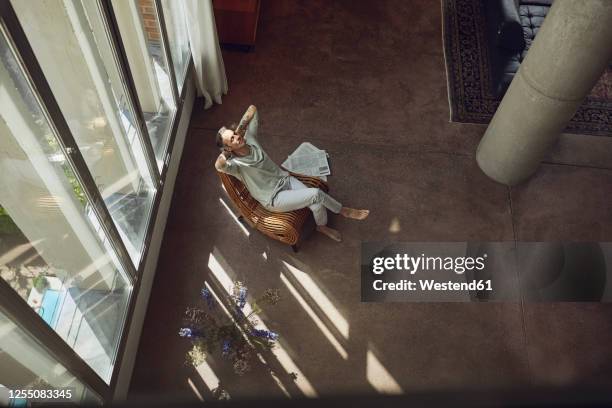 senior man relaxing on a chair in a loft flat - build wealth stockfoto's en -beelden