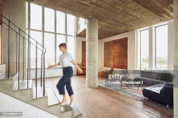 woman walking up stairs in a loft flat - blurred motion home stock pictures, royalty-free photos & images