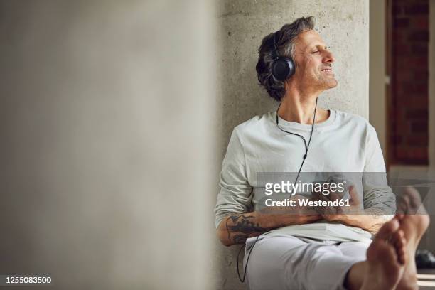 senior man with headphones listening music in a loft flat - 60 64 jahre stock-fotos und bilder