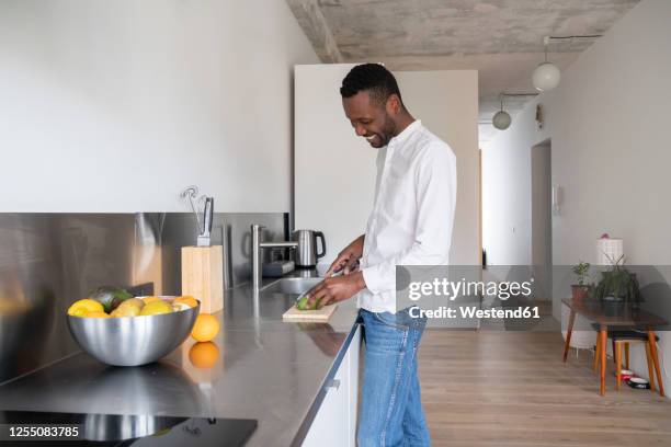 smiling man slicing avocado in kitchen - man cut out stock pictures, royalty-free photos & images