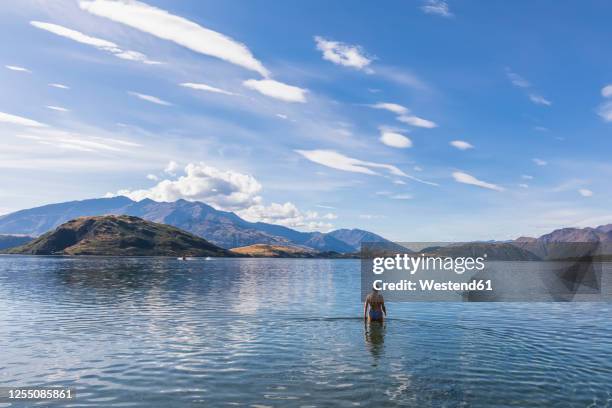 new zealand, queenstown-lakes district, glendhu bay, female tourist standing waist deep in lake wanaka - wade stock pictures, royalty-free photos & images